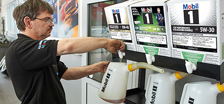 Mechaniker gießt Motoröl Bild