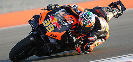 Motorradfahrer auf einem Red Bull-Motorrad, das sehr schnell um eine Kurve fährt