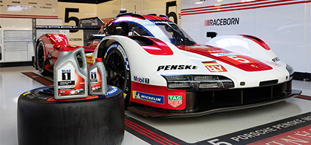 Porsche-Rennwagen in der Garage mit einer Mobil 1 Flasche auf einem Reifen vor dem Auto