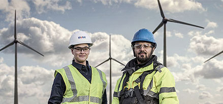 Mitarbeiter und Kunde von Mobil vor einem Windpark