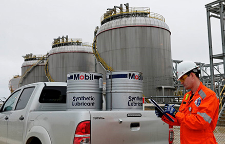 Mobil Synthetic Lubricant barrels behind male worker with clipboard
