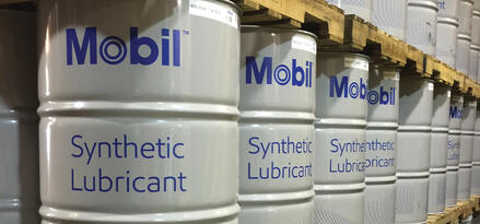 Mobil™ Synthetic Lubricant Fässer auf Paletten in einem geordneten Lagergang.